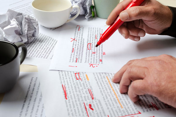 Person making a lot of edits to paper with red pen.